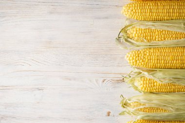 Beyaz ahşap bir arka planda taze nasır kulakları, üst manzara. Metin için yer.