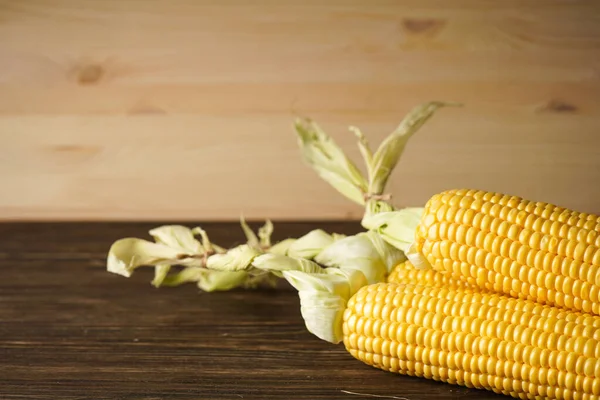 Tahta bir arka planda olgun mısır başakları.