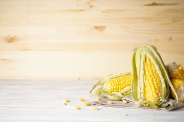 Beyaz ahşap zemin üzerinde olgun çiğ mısır koçanları.