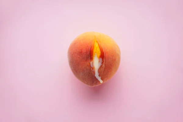 Pembe arka planda sulu şeftali ve yoğunlaştırılmış süt, üst manzara. Seks konsepti.