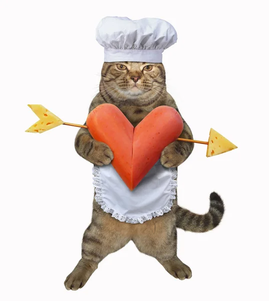 The cat chef holds a a heart-shaped sausage pierced with an arrow. White background.
