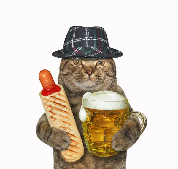 The beige cat in a hat is eating a hot dog and drinking beer from a mug. White background. Isolated.