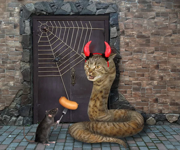 The beige cat snake with devil horns and the black rat with a sausage  on a fork are guarding the door of an old castle for Halloween.
