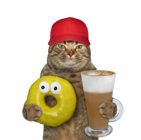 Beżowy Kot Czerwonej Czapce Trzyma Żółtego Pączka Szklankę Cappuccino Białe — Zdjęcie stockowe