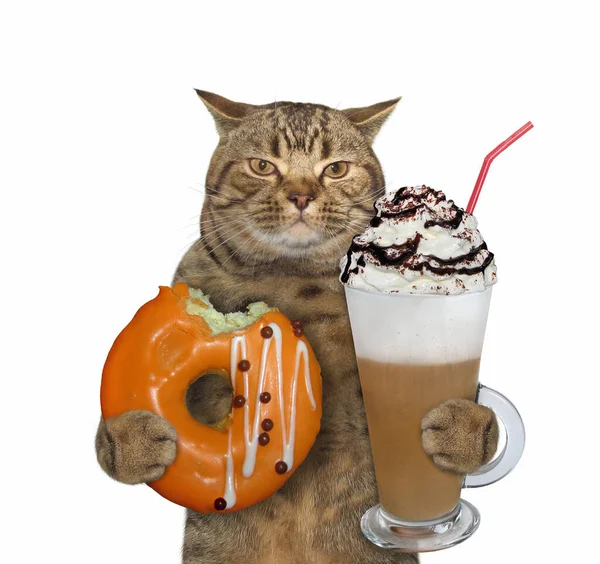 这只米色的猫手里拿着一只被橙色咬的甜甜圈和一杯卡布奇诺咖啡 还有一根吸管 白色背景 被隔离了 — 图库照片