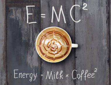 Krem şantili bir fincan kahve komik formüllerle dolu gri tahta bir masanın üzerinde..