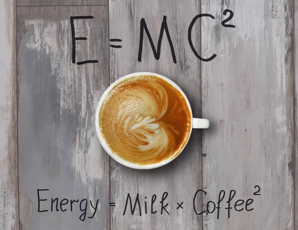 Krem şantili bir fincan kahve komik formüllerle dolu gri tahta bir masanın üzerinde..