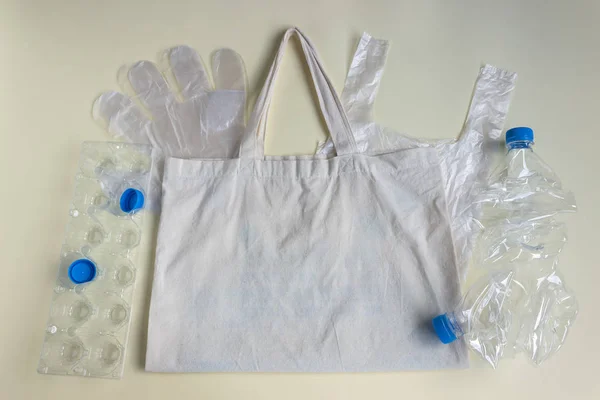 On the cloth reusable bag lie cellophane disposable bags, gloves, egg storage container, crumpled plastic bottles. Recycling concept , environmental pollution.