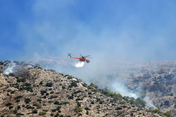 Fire helicopter extinguishes the fire on the hillside . Greece.