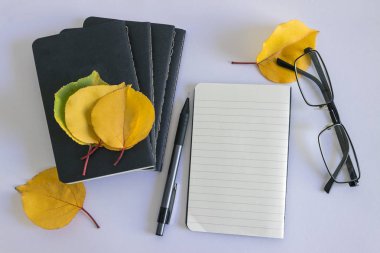 Notlar ve beyaz zemin üzerine sarı yapraklar için siyah not etmek. Kavram-sonbahar, yaratıcı ruh hali ve konfor.