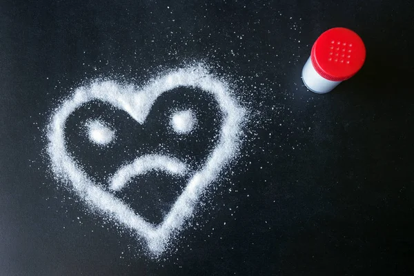 소금은 표면에 흩어져 있습니다 얼굴로 그려진된 심장입니다 다이어트 설탕의 소비에서 — 스톡 사진