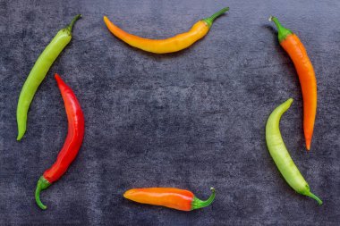 Farklı renkler koyu taş zemin üzerine sıcak biber biber. Kavram - sıcak haber, baharatlar, yemek tarifleri, baharatlar. Kopya alanı.