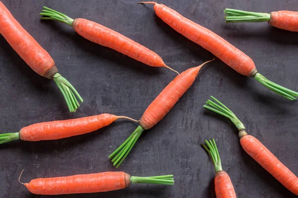 Bright ripe carrots with leaves on the table. Concept-healthy food, vegetarianism, raw food, a source of carotene and vitamins A,B .