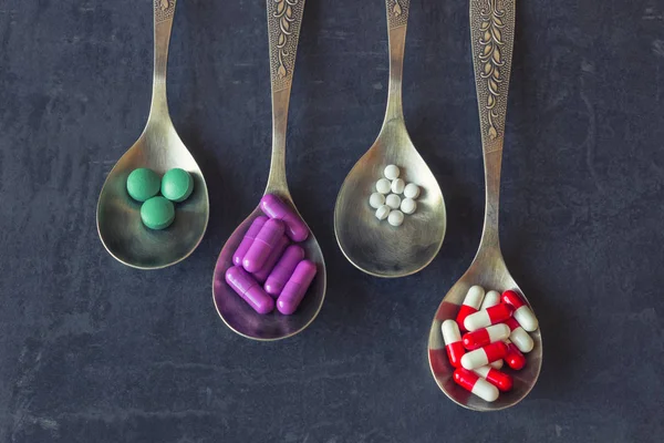 Bir sürü bir kaşık karanlık bir arka plan üzerinde renkli hapları ve ilaçlar, vitaminler, kapsül. Kavram-eczane, gıda katkı maddeleri, kötüye kullanımı ve bağımlılığı ilaç ilaçlar, uyuşturucu bağımlılığı.