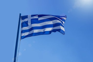 Yunan bayrağı mavi gökyüzü güneş önce sallayarak. Diplomasi kavramı, uluslararası ilişkiler.