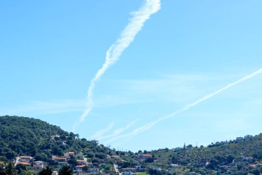 Trace of the plane in the blue sky. Sunny day. Greece. Concept- travel, vacation,  geoengineering and chemtrails.  clipart