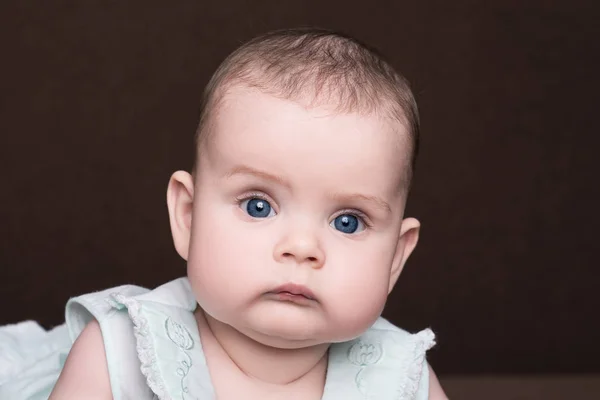 yaz elbise koyu kahverengi zemin üzerinde büyük mavi gözlü ciddi bebek kız portre kadar yakın