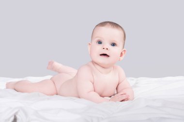 sevimli gülümseyen bebek kız mı erkek iri mavi gözlü gri arka plan üzerinde izole yumuşak battaniye çıplak yatıyor