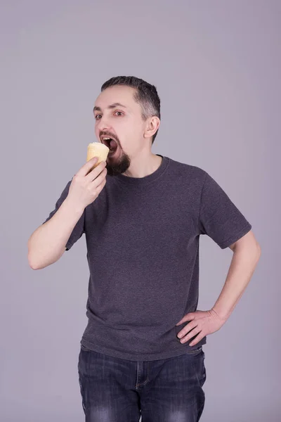 Mann mit Bart isst Eis vor grauem Hintergrund — Stockfoto