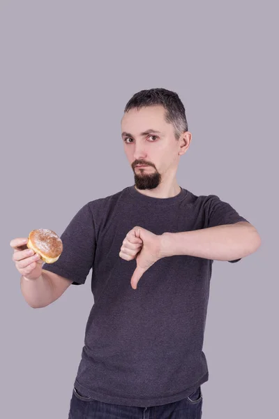 Mann mit Bart isst Brötchen vor grauem Hintergrund — Stockfoto