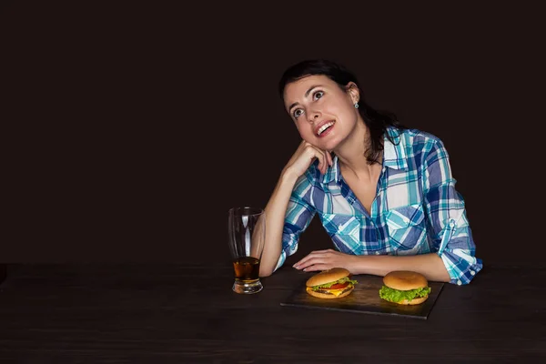 Smiling woman with a mug of beer and hamburgers isolated on brown — Stock Photo, Image