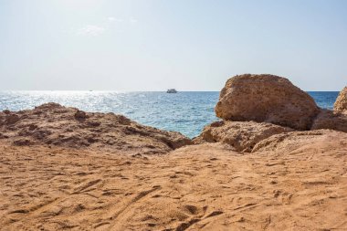 kum höyükleri, taş uçurum, mavi deniz ve gökyüzü ile bir plaj manzara