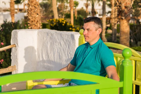 Adam renkli bir bankta oturur ve mesafe içine bakar Telifsiz Stok Fotoğraflar