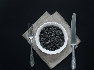 Ayçiçeği çekirdeği ile bir yemek ve karanlık bir arka plan yanında çatal bıçakla lianna peçeteye var.