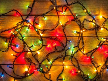 Ahşap bir arka plan üzerinde işte çeşitli renklerde yeşil, mavi, kırmızı, sarı ışık ile parlayan bir elektrik Festival çelenk