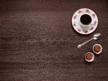 İki fincan kahve bir fincan tabağı üzerinde boşluk yatay olarak ahşap bir zemin üzerine bir çay kaşığı kağıt rozet candies