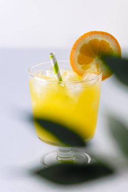 Lezzetli portakal suyu cam buz küp mavi ve beyaz arka plan taze portakal dikey