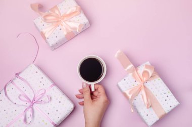 Tatil tebrik kartı Kupası kahve üstten görünüm yağ tutan kadın elini pembe arka plan tatil armağan ya da alışveriş satış kavramı üzerinde mevcut hediye kutusu