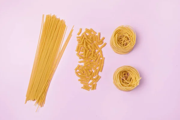 Kuru Makarna Makarnası 'nın Türleri ve Şekilleri Tagliatelle Fusilli Üst Görünüm Pembe Arkaplan