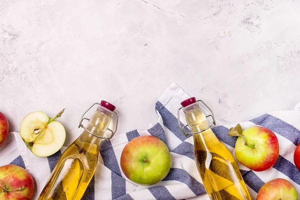 Bottles of Apple Vinegar and Ripe Apples on Kitchen Towel Light Gray Background Harvest Autumn Background Copy Space Apple Cider