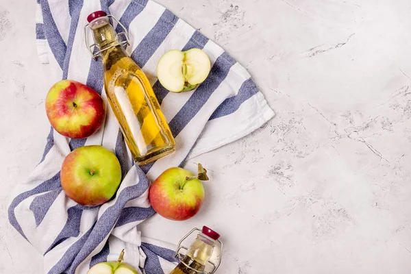 Bottles of Apple Vinegar and Ripe Apples on Kitchen Towel Light Gray Background Flat Lay Copy Space Apple Cider