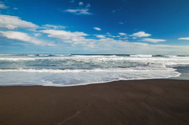 Halaktyr plaj. Kamçatka. Rusya Federasyonu. Karanlık neredeyse siyah renkli kum beach Pasifik Okyanusu. Taş dağları ve sarı çim bir arka plan üzerinde vardır. Hafif mavi gökyüzü.