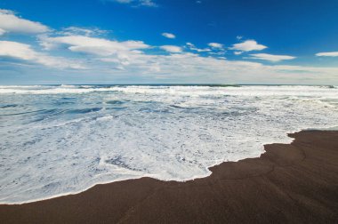 Halaktyr plaj. Kamçatka. Rusya Federasyonu. Karanlık neredeyse siyah renkli kum beach Pasifik Okyanusu. Taş dağları ve sarı çim bir arka plan üzerinde vardır. Hafif mavi gökyüzü.