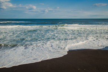Halaktyr plaj. Kamçatka. Rusya Federasyonu. Karanlık neredeyse siyah renkli kum beach Pasifik Okyanusu. Taş dağları ve sarı çim bir arka plan üzerinde vardır. Hafif mavi gökyüzü