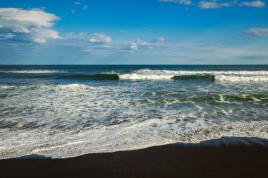 Halaktyr plaj. Kamçatka. Rusya Federasyonu. Karanlık neredeyse siyah renkli kum beach Pasifik Okyanusu. Taş dağları ve sarı çim bir arka plan üzerinde vardır. Hafif mavi gökyüzü