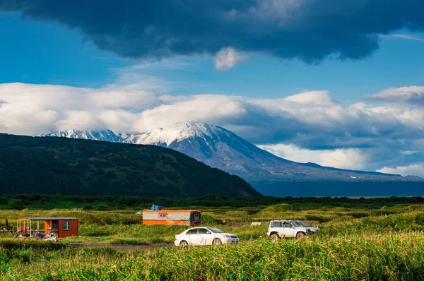 Halaktyr-Strand. kamchatka. Russische Föderation. dunkle fast schwarze Farbe Sandstrand des Pazifischen Ozeans. Steinberge und gelbes Gras sind auf einem Hintergrund zu sehen. hellblauer Himmel — Stockfoto