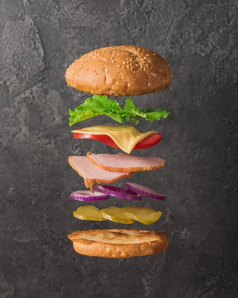 Fresh sandwich with flying ingredients isolated on concrete background