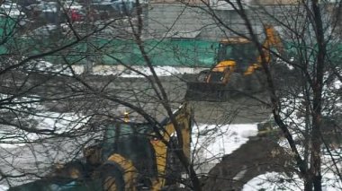 Kışın kar altında bir şantiye topraklarında küçük Ekskavatör digs