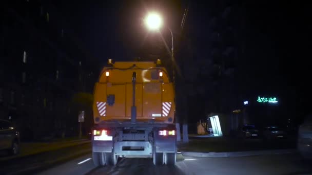 O aspirador de pó do carro vai para a frente e limpa a rua à noite na frente da câmera e afasta . — Vídeo de Stock