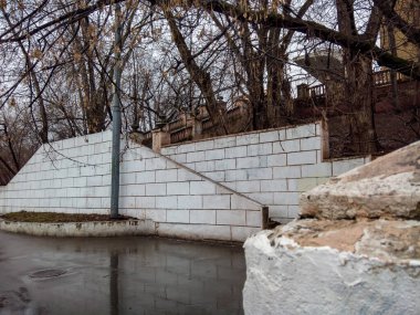 MOSCOW, RUSSIA - 2 Mart 2020: terk edilmiş bir Sovyet binasına uzanan ıslak basamaklı eski bir merdiven, çıplak ağaçların arasından, bir çitin arkasından. Çekiç ve Orak Fabrikası Kültür Sarayı