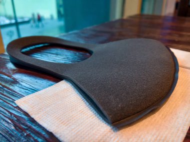 Siyah köpük malzemelerden oluşan koruyucu bir maske, bir kafenin arka planındaki beyaz bir peçetenin üzerine yerleştirilir.