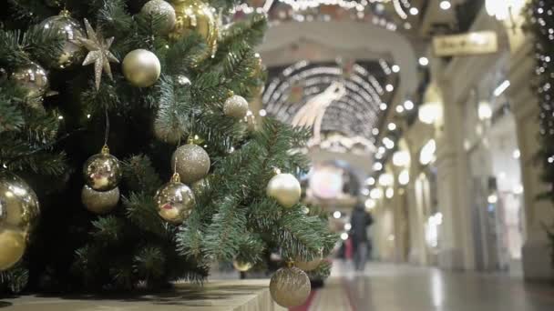 Árbol de Navidad decorado con diferentes bolas de oro. La gente pasa desenfocada. — Vídeo de stock
