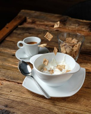 Mısır gevreği süt bir kase içine falllig vardır. Bardak Kuru mısır gevreği ve ahşap zemin üzerine kahve