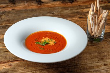 Peynir ve yeşil otlar ile sebze domates çorbası. Grisini rustik ahşap arka plan üzerinde bardak