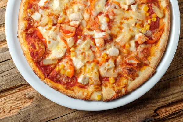 Pizza with chicken, corn and pineapple on wood background. Top view