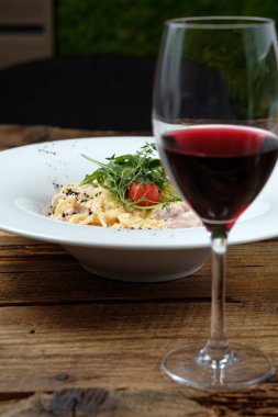 Bardak kırmızı şarap ve peynirli makarna woode masada